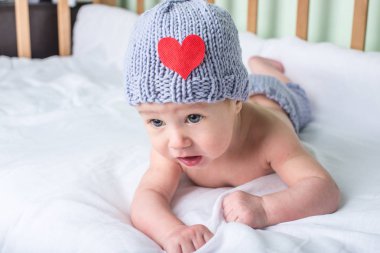 Mutlu bebek beşik üzerinde bir kalp ile örme bere bir battaniyeye yalan söylüyor. Annelik ve vahşi kavramı