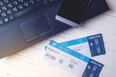 Bir telefon ve dizüstü bilgisayar ile masada iki bilet vardır. Kavramı için seyahat online bilet rezervasyon satın alma