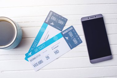 Bir fincan kahve uçak biletleri, telefon ve laptop Beyaz ahşap zemin üzerinde. Online bilet rezervasyon satın alma kavramı