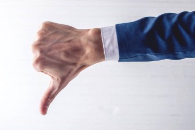 İşadamı başparmak aşağı gösterilen takım elbiseli erkek el