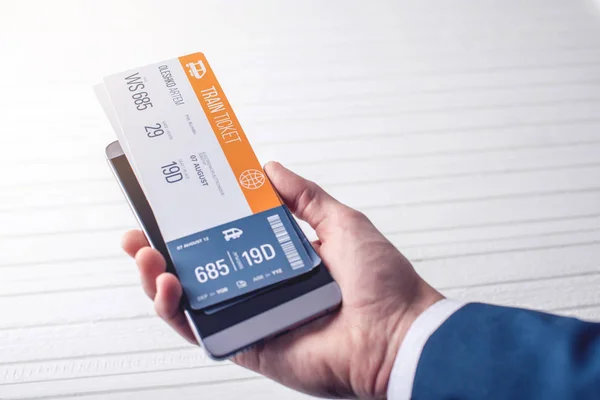 The hand holding the phone with the train tickets. Concept of online purchase and booking of tickets for travel — Stock Photo, Image