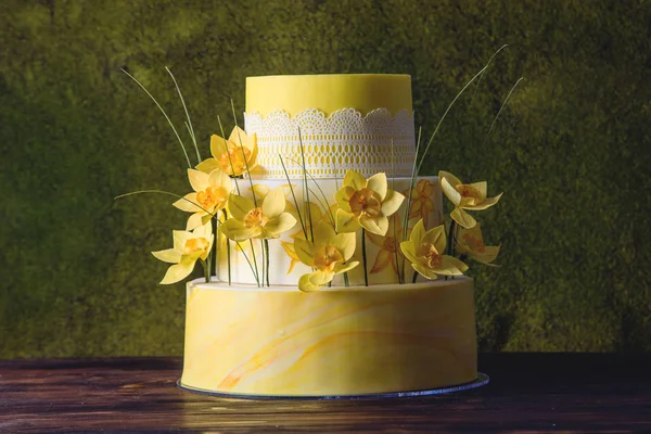 Hermosa casa amarilla boda pastel de tres niveles decorado con flores de primavera roja. Concepto de tendencias florales en postres —  Fotos de Stock