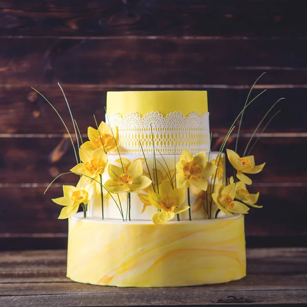 Hermosa casa amarilla boda pastel de tres niveles decorado con flores de primavera roja. Concepto de tendencias florales en postres —  Fotos de Stock