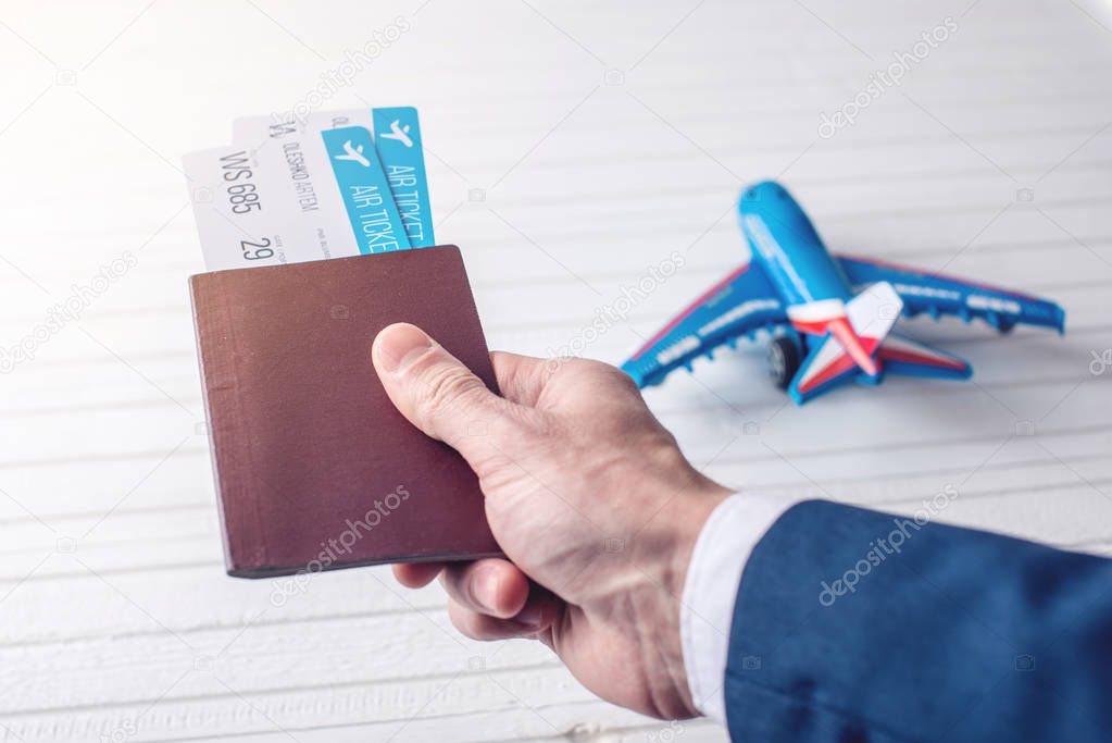 Hand holding passport with plane tickets on a white background. Concept of business travel