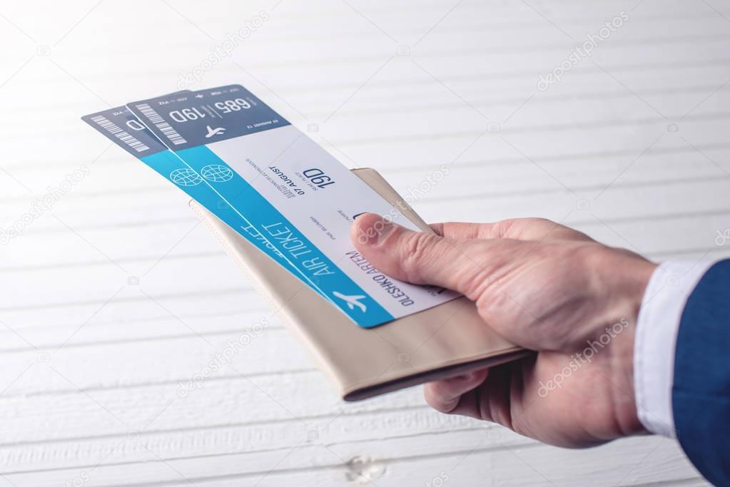 Hand holding passport with plane tickets on a white background. Concept of business travel