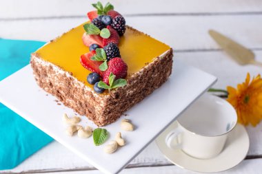 Ev yapımı kare kek üstüne sarı jelly ve meyveleri açık renkli nane ile dekore edilmiş.