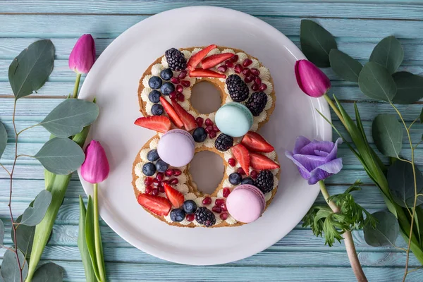 Cake in shape of number 8 decorated with berries and flowers tulips. Dessert for women\'s day on the eighth of March