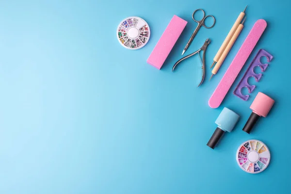 Manikür ve pedikür mavi bir arka plan üzerinde kozmetik araçlar kümesi. Jel cilalar, törpü ve kesme makineleri, üstten görünüm
