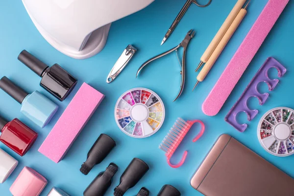 Manikür ve pedikür mavi bir arka plan üzerinde kozmetik araçlar kümesi. Jel cilalar, törpü ve kesme makineleri, üstten görünüm