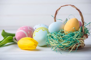 Renkli Paskalya yumurtaları Sarı Lale el ile beyaz bir ahşap zemin üzerine boyalı. Festival bahar kartı