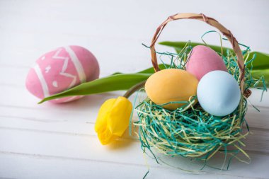 Renkli Paskalya yumurtaları Sarı Lale el ile beyaz bir ahşap zemin üzerine boyalı. Festival bahar kartı