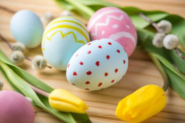 Bir ışık ahşap arka plan üzerinde renkli Paskalya yumurtaları Sarı Lale el ile boyalı. Festival bahar kartı