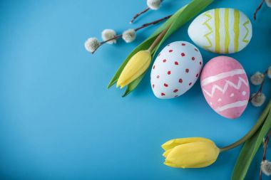 Renkli Paskalya yumurtaları Sarı Lale el ile mavi bir arka plan üzerine boyalı. Tatil bahar kartı