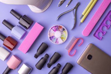 Manikür ve pedikür mor bir arka plan üzerinde kozmetik araçlar kümesi. Jel cilalar, törpü ve kesme makineleri, üstten görünüm