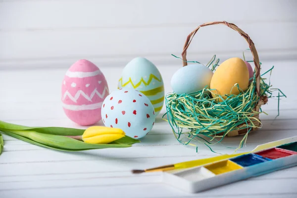 Uova di Pasqua colorate con vernici dipinte a mano su uno sfondo di legno bianco. Biglietto di primavera festivo — Foto Stock