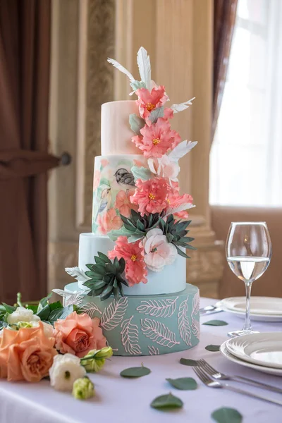 Huis voor lagen bruidstaart op de tafel in het restaurant versierd met roze rozen en groene bladeren in een rustieke stijl — Stockfoto