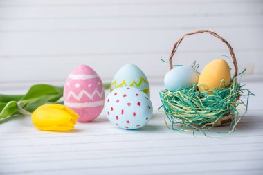 Renkli Paskalya yumurtaları Sarı Lale el ile beyaz bir ahşap zemin üzerine boyalı. Festival bahar kartı