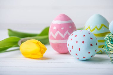 Renkli Paskalya yumurtaları Sarı Lale el ile beyaz bir ahşap zemin üzerine boyalı. Festival bahar kartı