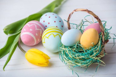 Renkli Paskalya yumurtaları Sarı Lale el ile beyaz bir ahşap zemin üzerine boyalı. Festival bahar kartı