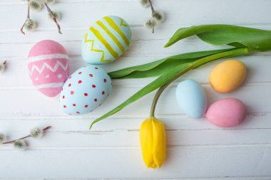 Renkli Paskalya yumurtaları Sarı Lale el ile beyaz bir ahşap zemin üzerine boyalı. Festival bahar kartı