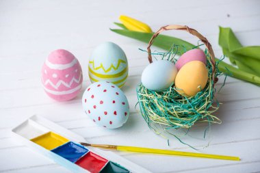 Renkli Paskalya yumurtaları boya el ile beyaz bir ahşap zemin üzerine boyalı. Festival bahar kartı