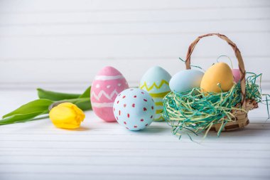 Renkli Paskalya yumurtaları Sarı Lale el ile beyaz bir ahşap zemin üzerine boyalı. Festival bahar kartı