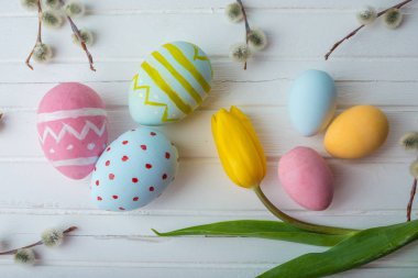 Renkli Paskalya yumurtaları Sarı Lale el ile beyaz bir ahşap zemin üzerine boyalı. Festival bahar kartı