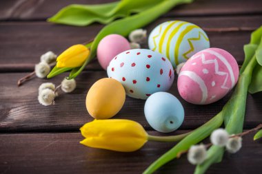 Koyu ahşap arka plan üzerinde renkli Paskalya yumurtaları Sarı Lale el ile boyalı. Tatil bahar kartı