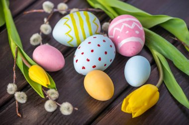 Koyu ahşap arka plan üzerinde renkli Paskalya yumurtaları Sarı Lale el ile boyalı. Tatil bahar kartı