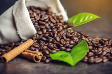 Kahve çekirdekleri ve yeşil yığını çanta içinde koyu arka plan üzerinde bırakır.