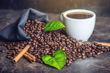 Beyaz Siyah espresso fincan kahve çekirdekleri ve yeşil yığını ile çanta içinde koyu arka plan üzerinde bırakır.