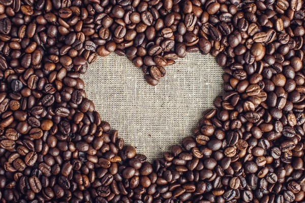 Textured background of coffee beans in heart-shaped top view. Concept love for a fresh and fragrant drink. — Stock Photo, Image