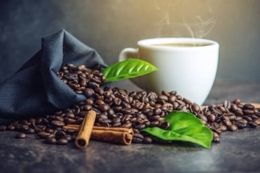 Beyaz Siyah espresso fincan kahve çekirdekleri ve yeşil yığını ile çanta içinde koyu arka plan üzerinde bırakır.