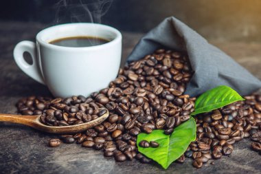 Beyaz Siyah espresso fincan kahve çekirdekleri ve yeşil yığını ile çanta içinde koyu arka plan üzerinde bırakır.