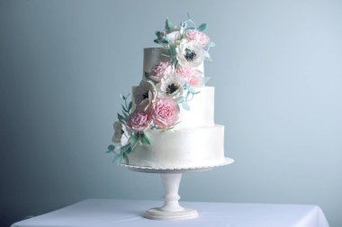 Güzel üç katmanlı beyaz düğün pastası, şeker pembe peonies çiçeklerle süslenmiş. Zarif tatil tatlılar kavramı