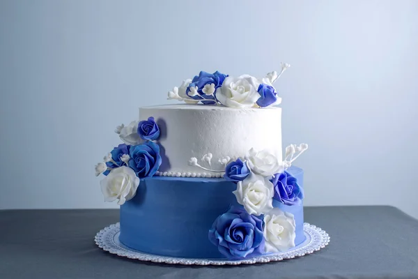 Hermoso pastel de boda de dos niveles blanco y azul decorado con flores rosas de azúcar. Concepto de elegantes postres navideños —  Fotos de Stock