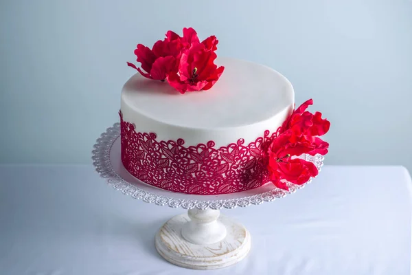 Білий весільний торт прикрашений квітами цукровими маками та червоним орнаментом. Концепція елегантних святкових десертів — стокове фото