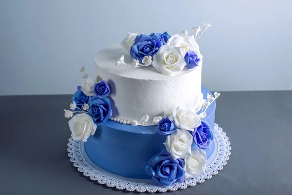 美しい 2 階層型白と青ウェディング ケーキは、砂糖のバラ花で飾られました。エレガントな休日のデザートのコンセプト — ストック写真
