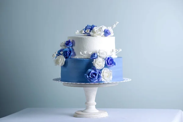 Belo bolo de casamento branco e azul de duas camadas decorado com flores rosas de açúcar. Conceito de sobremesas de férias elegantes — Fotografia de Stock