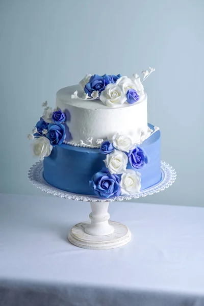 Vacker två prisdifferentierade vita och blå bröllopstårta dekorerad med blommor socker rosor. Begreppet elegant semester desserter — Stockfoto