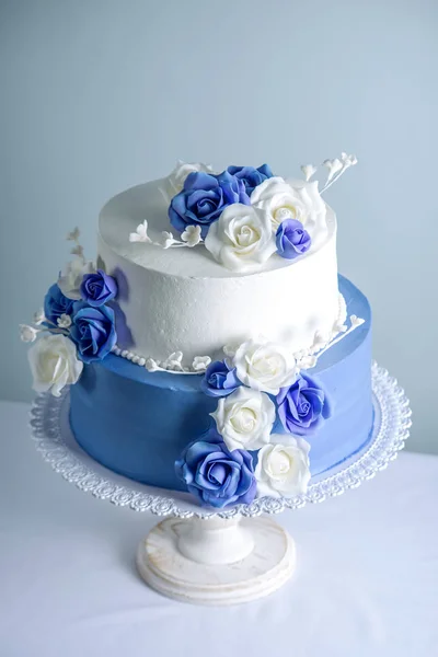 Belo bolo de casamento branco e azul de duas camadas decorado com flores rosas de açúcar. Conceito de sobremesas de férias elegantes — Fotografia de Stock