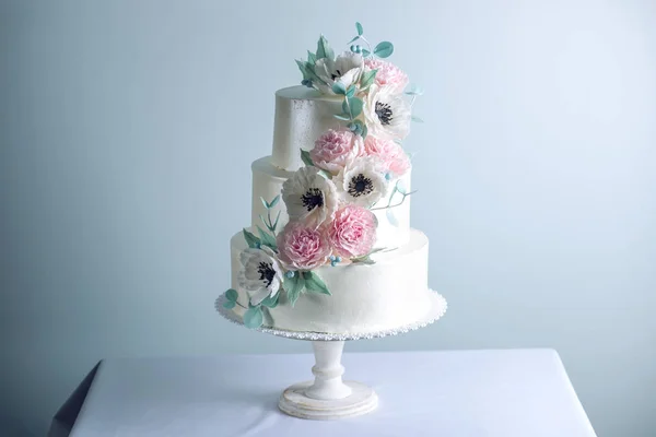 Gyönyörű három többszintű fehér esküvői torta díszített virágok rózsaszín cukor pünkösdi rózsa. Az elegáns holiday desszertek koncepció — Stock Fotó
