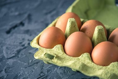 Taze çiftlik yumurtaları içinde güzel koyu arka plan üzerinde yeşil tepsi. Ev çevre dostu ürünler