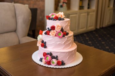 Üç katmanlı pembe düğün pastası meyveler ve çiçekler ile dekore edilmiştir. Kavram Pastane şeker mastik bitki