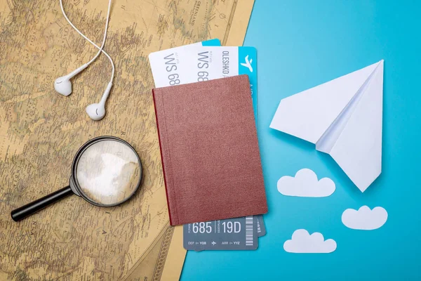 Авиабилеты с паспортом и бумажным самолетом на фоне карты мира, вид сверху. Концепция авиаперелетов и праздников — стоковое фото