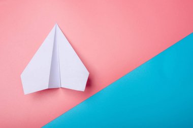 Pastel renkler arka plan üzerinde beyaz kağıt origami uçak yatıyor