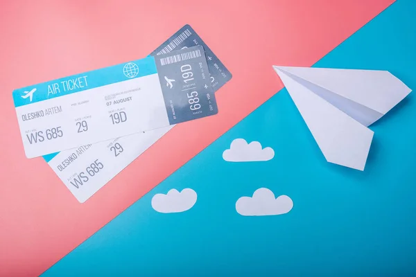 Air tickets and paper plane on pastel background, topview. Concept of air travel and holidays
