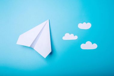 Pastel mavi zemin üzerine beyaz kağıt origami uçak yatıyor