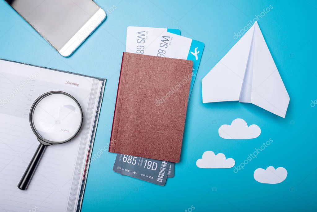 Air tickets with passport and paper plane on blue background, topview. The concept of air travel and holidays