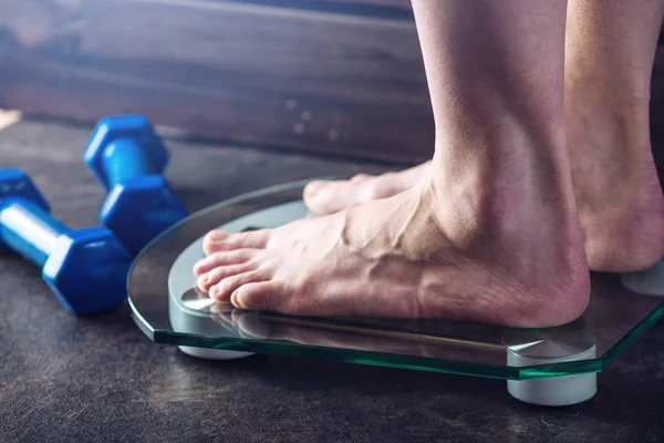 Piedini femminili in piedi su bilance elettroniche per il controllo del peso su fondo scuro. Concetto di allenamento sportivo, diete — Foto Stock